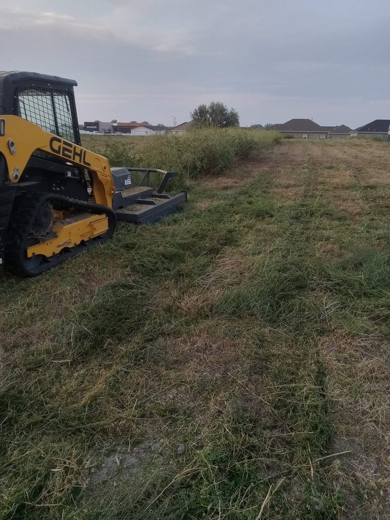 Brush cutter on the skid steer knocking down heavy weeds on a lot.